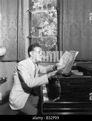 Uomo al pianoforte con foglio di musica Foto Stock