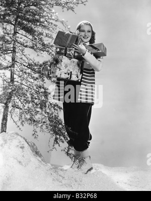 La donna al di fuori nella neve con i regali di Natale Foto Stock