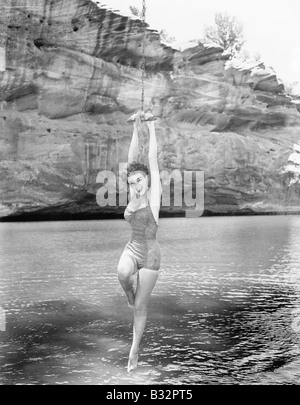 Donna pendenti da swing corda su acqua Foto Stock