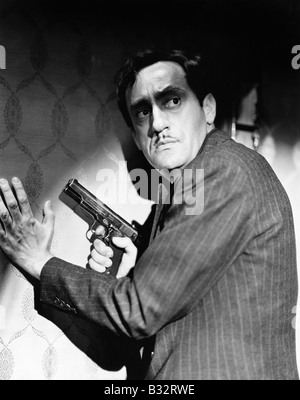 Profilo di un gangster tenendo un arma guardando sopra la sua spalla Foto Stock