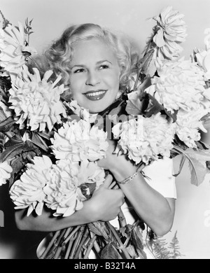 Ritratto di una giovane donna tenendo un mazzo di fiori cercando felice Foto Stock