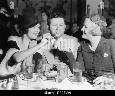 Due donne accendere una sigaretta per un uomo Foto Stock