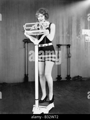 Giovane donna su una scala prendendo il suo peso Foto Stock