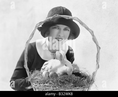 Giovane donna con un cesto di Pasqua e un coniglietto Foto Stock