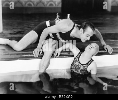 Uomo di piegarsi a baciare una donna in piscina Foto Stock