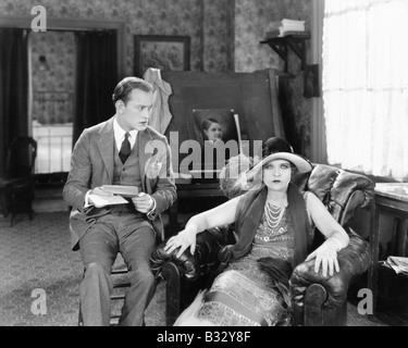 L uomo e la donna seduta in un salotto lettura di una lettera e guardando sorpreso Foto Stock
