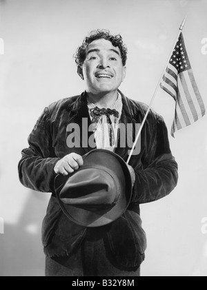 Uomo con la bandiera americana nella sua mano sorridente Foto Stock