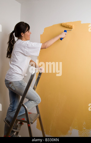 Giovane donna dipinge la sua casa Foto Stock