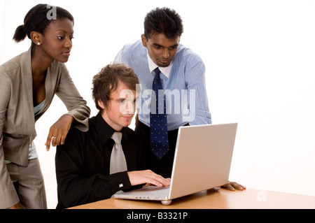 Un imprenditore è al lavoro su un notebook come due colleghi guardano su Foto Stock