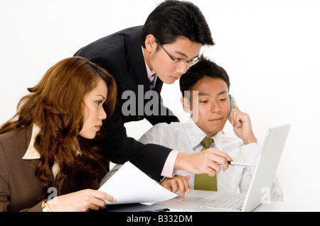 Un team di occupato di tre lavorando sul portatile e telefono Foto Stock