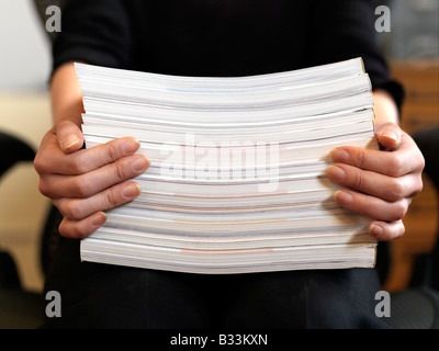 Una vista ravvicinata di mani femminili con in mano una risma di carta mentre è seduto Foto Stock