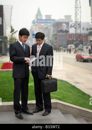 Chinesemen discutere circa le informazioni su un documento. Foto Stock