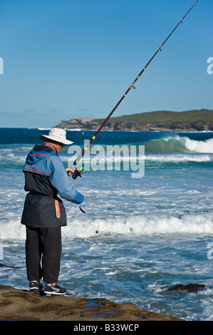 La pesca di roccia: uomo di pesca in mare sulle rocce Foto Stock