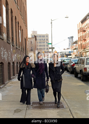 Tre giovani donne asiatiche a piedi lungo una strada di città durante la stagione invernale a conversare e ridere Foto Stock