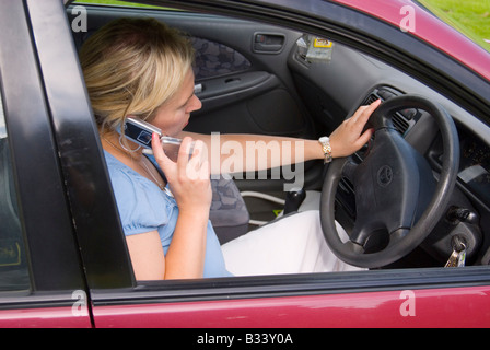 Donna che parla al telefono cellulare durante la guida Foto Stock