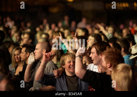 Tre giovani uomini godendo cantando e urlando in mezzo alla folla ad un concerto rock Foto Stock