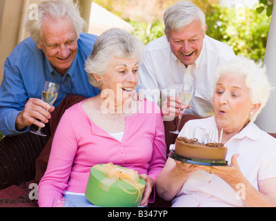 Due coppie sul patio con torta e dono sorridente Foto Stock