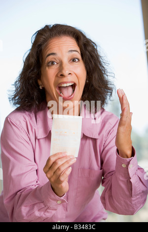 Donna con la vincita del biglietto della lotteria eccitato e sorridente Foto Stock