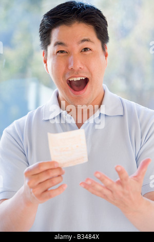 L'uomo con la vincita del biglietto della lotteria eccitato e sorridente Foto Stock