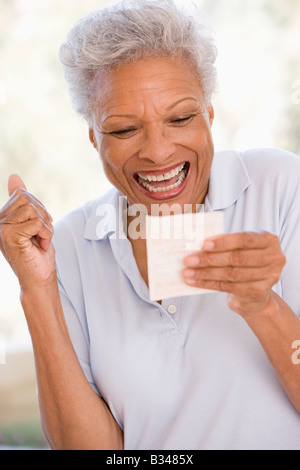 Donna con la vincita del biglietto della lotteria eccitato e sorridente Foto Stock