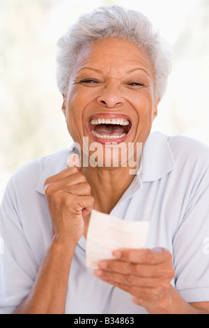 Donna con la vincita del biglietto della lotteria eccitato e sorridente Foto Stock