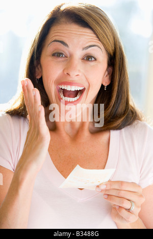 Donna con la vincita del biglietto della lotteria eccitato e sorridente Foto Stock