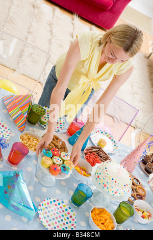 Donna al partito impostando il cibo e sorridente Foto Stock