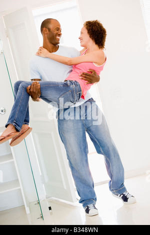 Il marito tenendo la moglie nella nuova casa sorridente Foto Stock