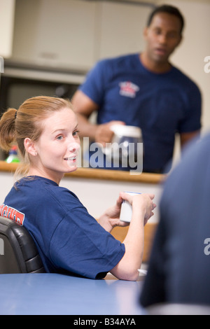 Tre i vigili del fuoco in sala pausa con uno il caffè in background (messa a fuoco selettiva) Foto Stock