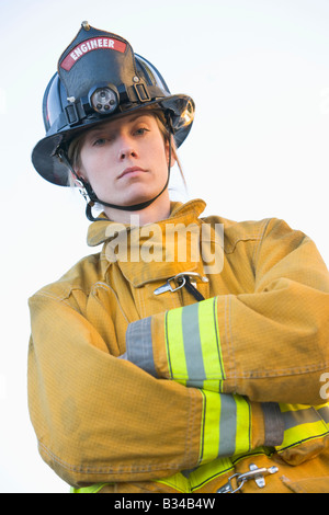 Firewoman all'aperto in piedi indossando il casco Foto Stock