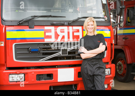 Firewoman in piedi nella parte anteriore del motore Fire Foto Stock