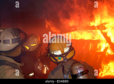 Vigili del fuoco combattimenti dentro le fiamme una casa Foto Stock