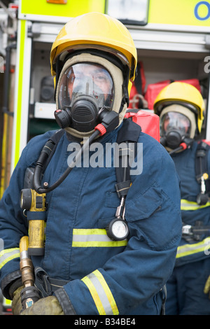 Due vigili del fuoco nelle maschere in piedi vicino a motore Fire (profondità di campo) Foto Stock