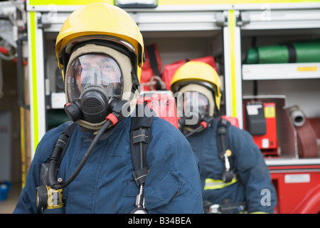 Due vigili del fuoco nelle maschere in piedi vicino a motore Fire (profondità di campo) Foto Stock