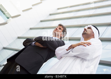 Due imprenditori in piedi all'aperto da edificio (alta chiave/messa a fuoco selettiva) Foto Stock