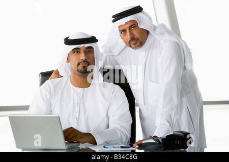 Due imprenditori in ufficio con computer portatile (alta chiave/messa a fuoco selettiva) Foto Stock