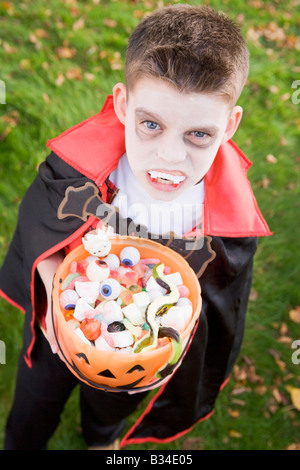 Ragazzo giovane all'aperto indossando il costume del vampiro in azienda di Halloween Candy Foto Stock