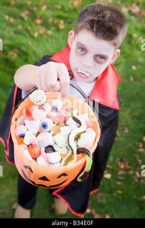 Ragazzo giovane all'aperto indossando il costume del vampiro in azienda di Halloween Candy Foto Stock