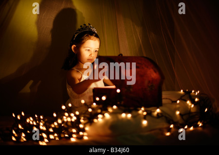 Il magico scrigno bambina di cinque anni si siede sul letto con baldacchino e apre una scatola Foto Stock