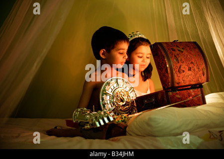 Il magico scrigno bambina di cinque anni e sei anni di vecchio ragazzo a giocare a fratello e sorella di razza mista Foto Stock