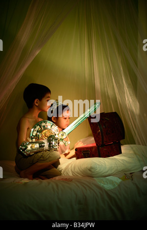 Il magico scrigno bambina di cinque anni e sei anni di vecchio ragazzo a giocare a fratello e sorella di razza mista Foto Stock