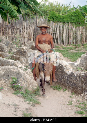 Kenya, Pate Island, Pate Village. Un abitante del villaggio di Pate cavalca il suo asino attraverso rovine sulla periferia della moderna Pate V Foto Stock