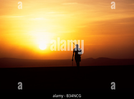 Kenya, Chalbi Desert, Kalacha. Un pastore Gabbra presenta una solitaria figura nel deserto Chalbi al tramonto. Il Gabbra sono un Cushitic tribù di pastori nomadi che vivono con le loro mandrie di cammelli e capre intorno la frangia del deserto Chalbi. Foto Stock