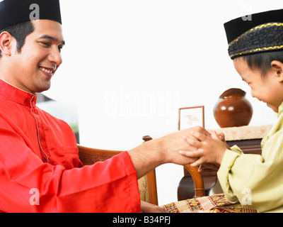 Padre e figlio saluto durante hari raya Foto Stock