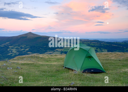 Una vista della Sugarloaf e una tenda piantato sulla Table Mountain in montagna nera del Galles del Sud al tramonto con una luna crescente Foto Stock