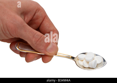 Cucchiaio con le pillole in mano isolato su bianco Foto Stock