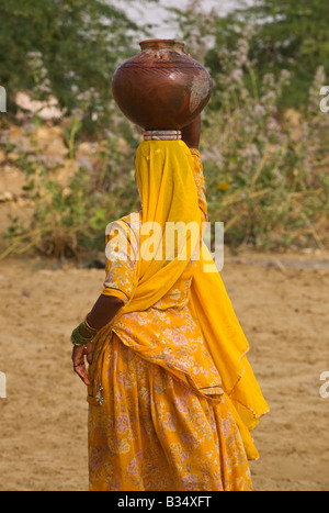 Un BANJARI TRIBESWOMAN porta acqua nel suo villaggio nel deserto di Thar vicino a Jaisalmer Rajasthan in India Foto Stock