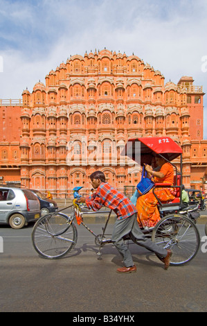 Un ampio angolo di visione della facciata del Hawa Mahal (palazzo dei venti) con un risciò ciclo essendo spinto in passato. Foto Stock