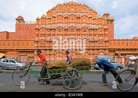 Un ampio angolo di visione della facciata del Hawa Mahal (palazzo dei venti) e un ciclo con un carico pesante essendo spinto in passato. Foto Stock