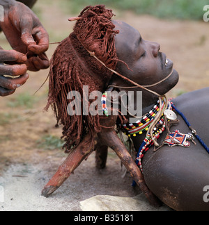 Kenya, Maralal, Lodokejek. Un Samburu guerriero ha il suo Ochred treccia di capelli da un amico. Foto Stock